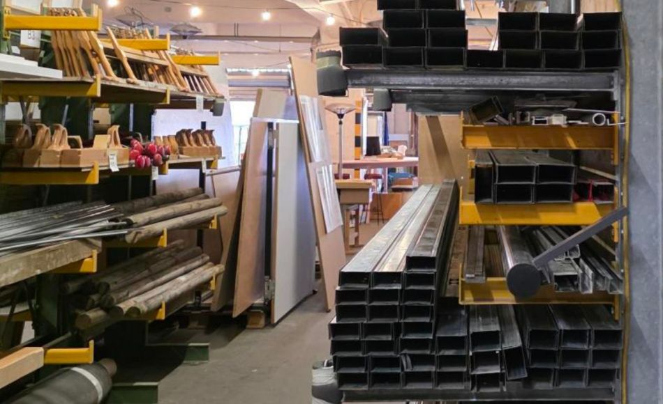 Foto aus dem Lager der Bauteilbörse: rechts Regale mit Metall-Leisten, im Hintergrund weitere Regale voller Werkzeug und anderem Material